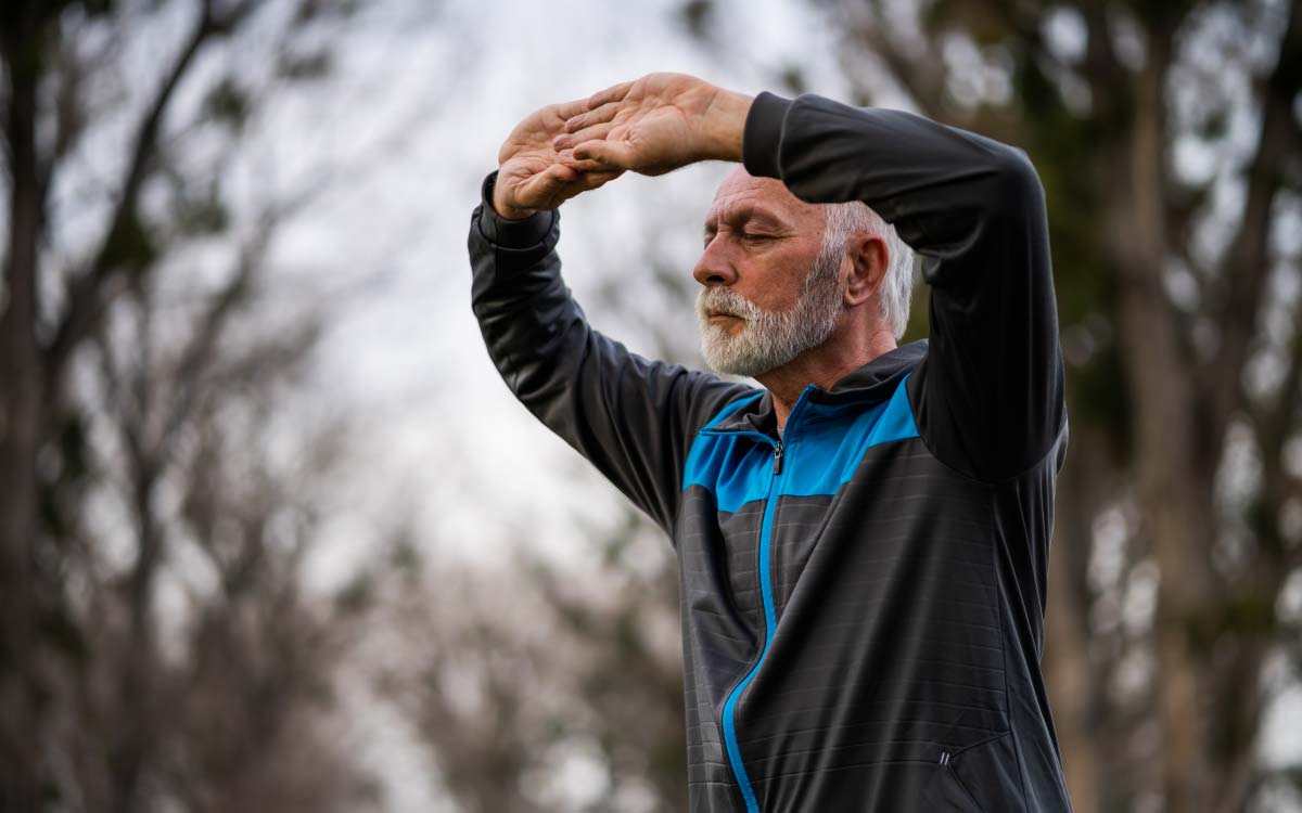 Dyn oedrannus yn gwneud Tai Chi y tu allan